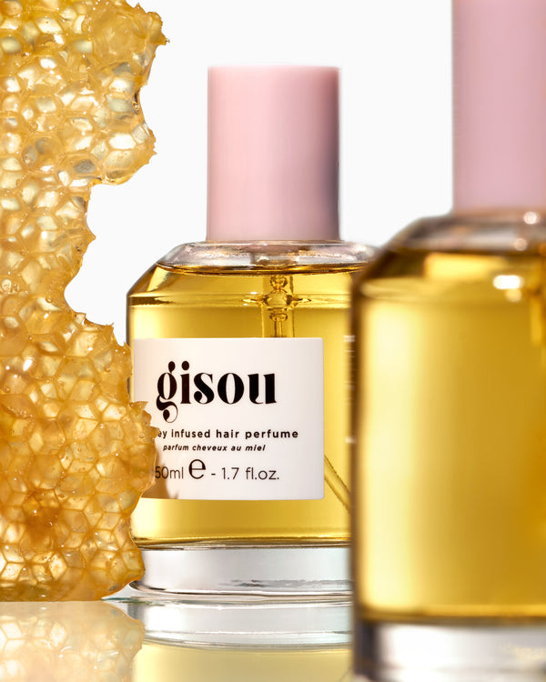 Two bottles of Honey Infused Hair perfume next to the honey comb
